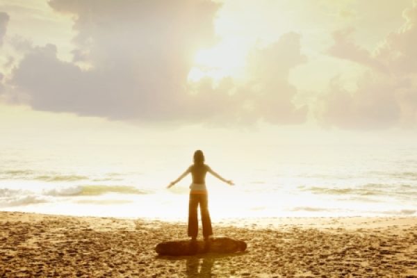 a person stands on a beach with arms open wide