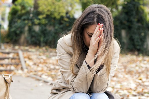 a woman sits wth hands on her forehead in sadness
