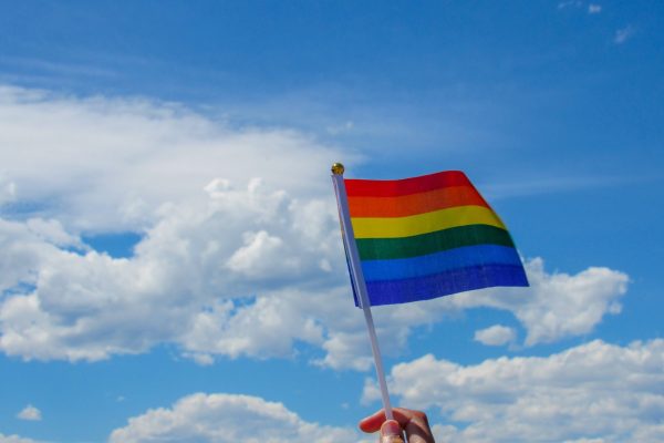 pride flag against a blue sky with white clouds