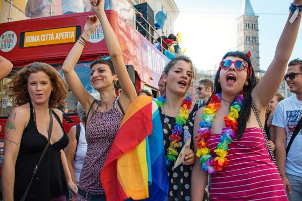 A group of people celebrating at a pride event with rainbow flags and leis, showing joy and support for LGBTQ+ rights.