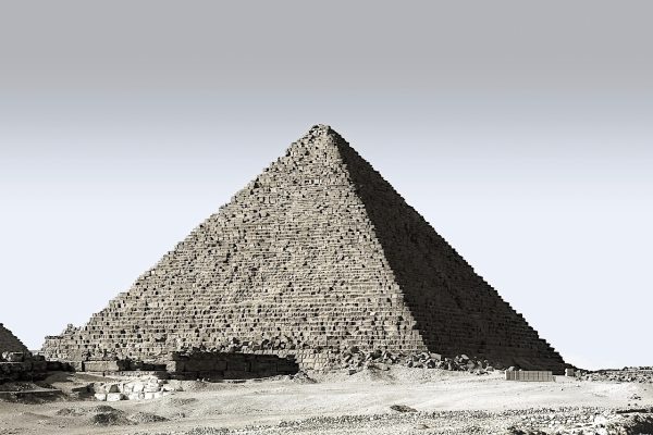 The Great Pyramid of Giza under a clear sky, surrounded by desert sand.
