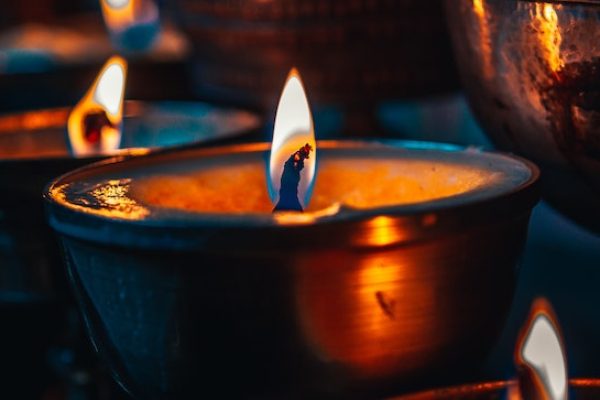 Close-up of a lit candle in a brass holder, surrounded by a warm, dimly lit ambiance.
