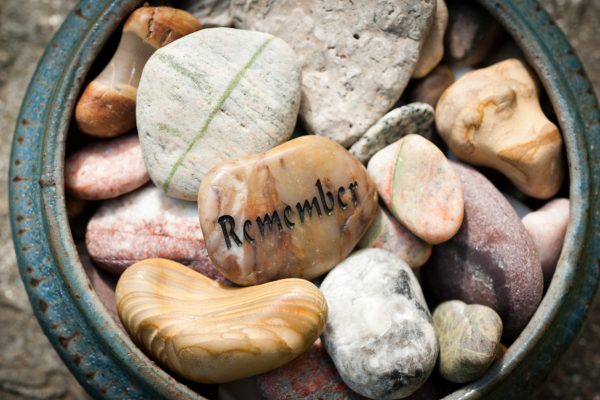 A bowl of various polished stones, with the word Remember engraved on the central stone.