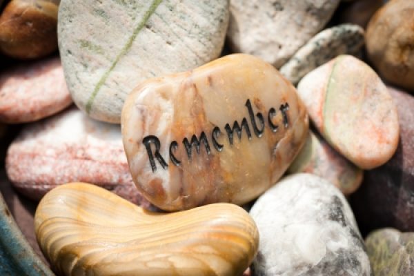 Smooth stones piled together, with one featuring the word Remember carved into it.