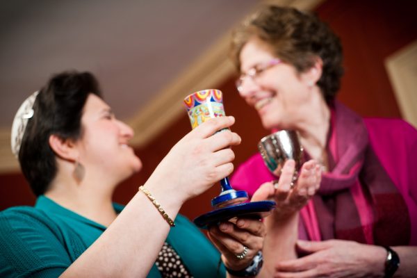Two people smiling and clinking colorful cups in a celebratory gesture.