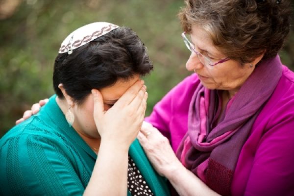 A comforting hug between two women, one with her hand on her face.