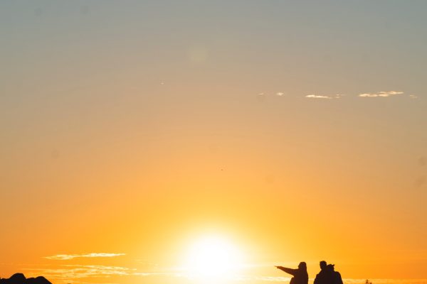 two people sit before a sunrise