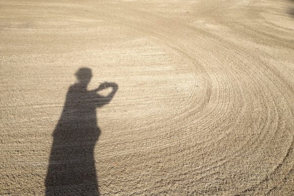 a woman in shadow across the sand