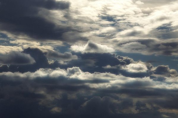 Dark, dramatic clouds fill the sky, with sunlight peeking through gaps, creating a moody atmosphere.