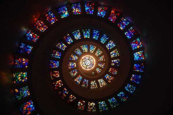 Spiral stained glass ceiling with colorful geometric patterns, viewed from directly below, forming a glowing center.