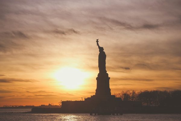 silhouette of the Statue of Liberty against a sunset