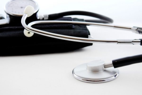 Close-up of a stethoscope and blood pressure cuff on a white surface.