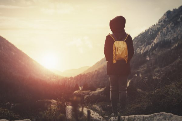 a person walks towards a sunset in the valley