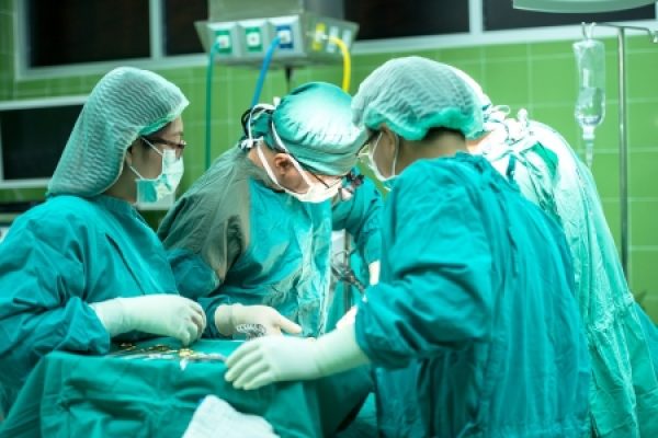 Surgical team in green scrubs performing surgery in an operating room.