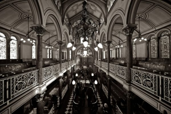 a black and white photo of a long sanctuary lined with a second story of benches
