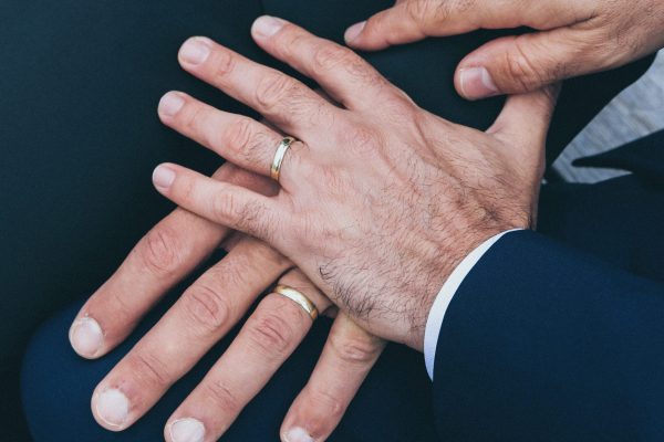 two mens hands with wedding rings