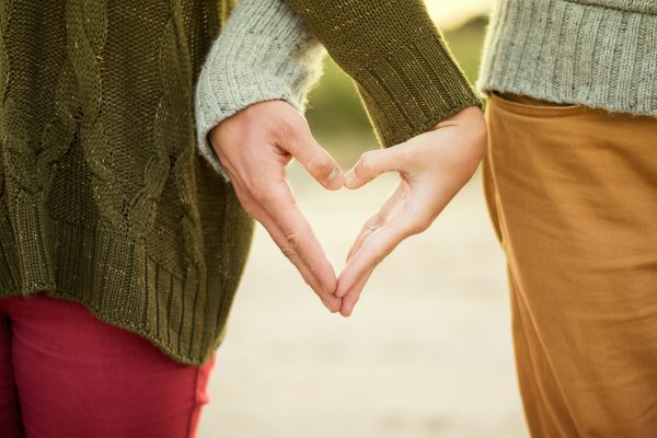 two peoples hands making a heart shape together