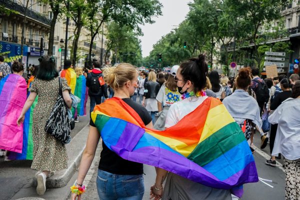 two women wrapped in a pride flag walking in a pride parade