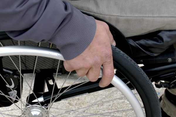 a close up of a hand holding the rim of a wheelchair