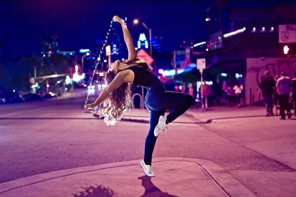 woman dancing with string lights on a city street
