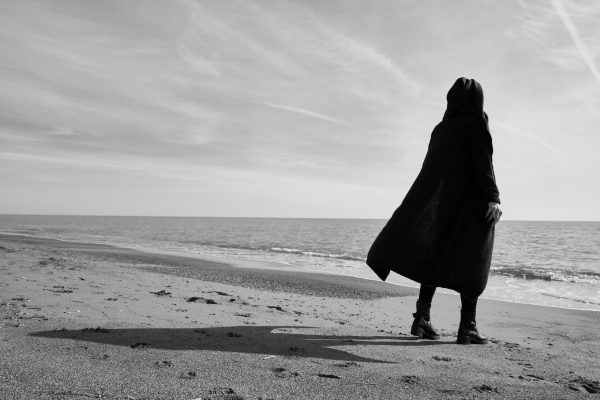 person in cape on beach