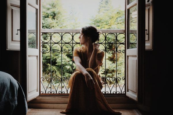 woman sitting in window seat, in profile, backlit