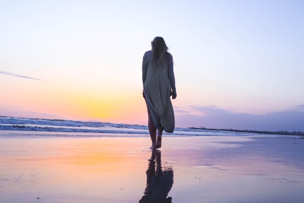 woman walking away on beach at sunrise