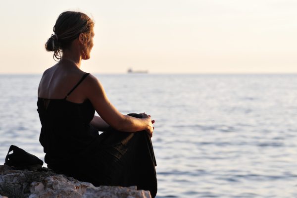 woman sits overlooking the sea